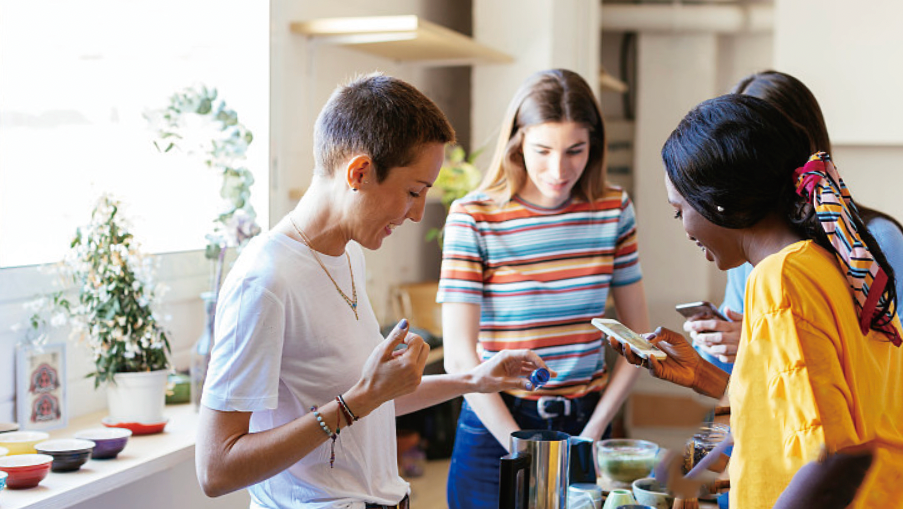 Three people looking over small bowls and ingredients on a counter